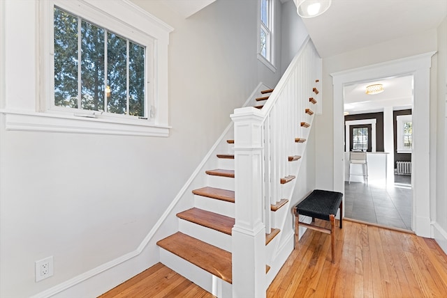 staircase featuring radiator, wood-type flooring, and plenty of natural light