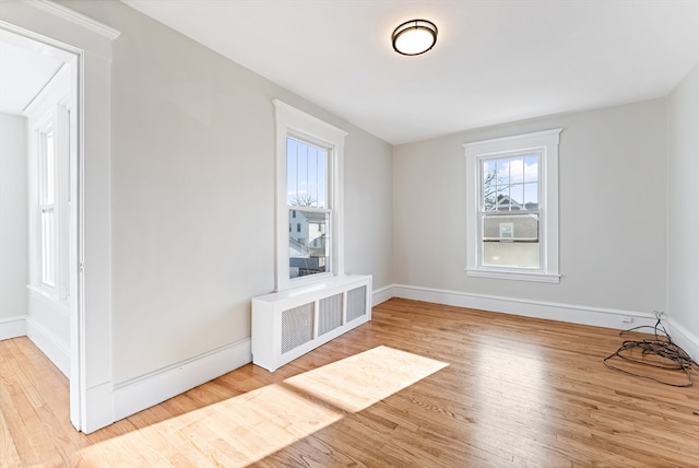 interior space featuring radiator heating unit and light hardwood / wood-style flooring