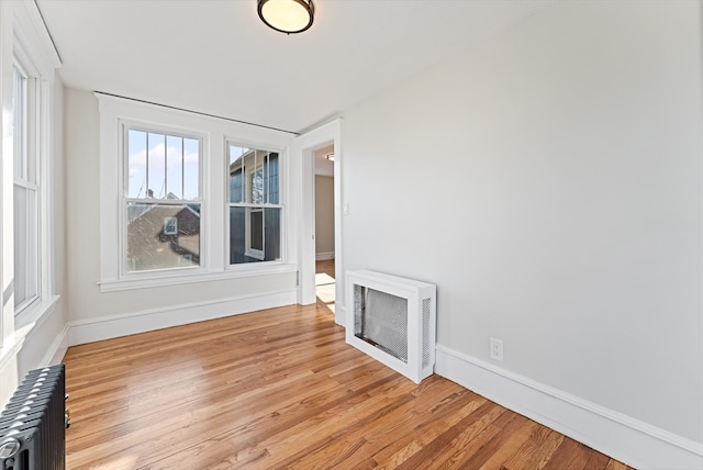 empty room with heating unit, radiator heating unit, and light hardwood / wood-style flooring