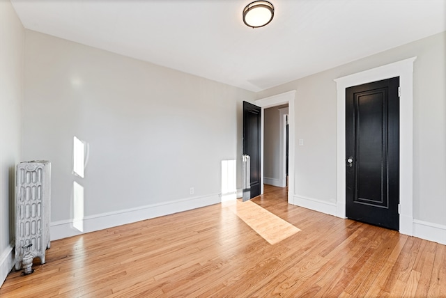 unfurnished bedroom featuring radiator and light hardwood / wood-style flooring