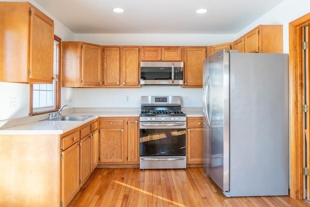 kitchen with stainless steel appliances, sink, and light hardwood / wood-style floors