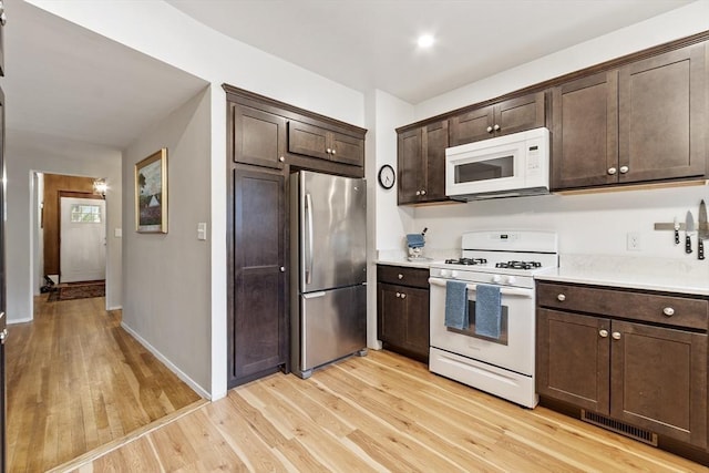 14 Thoreau St, Concord, MA 01742 - kitchen featuring white appliances, light wood-style flooring, dark brown cabinets, light countertops, and baseboards