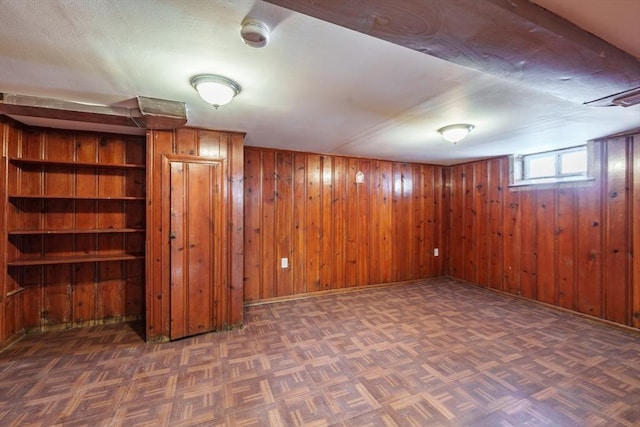 basement featuring dark parquet flooring and wooden walls