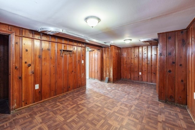 basement featuring dark parquet floors and wood walls