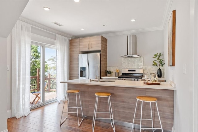 24 Lemon St Unit 2, Salem, MA 01970 - kitchen with wall chimney range hood, appliances with stainless steel finishes, tasteful backsplash, a kitchen bar, and light countertops