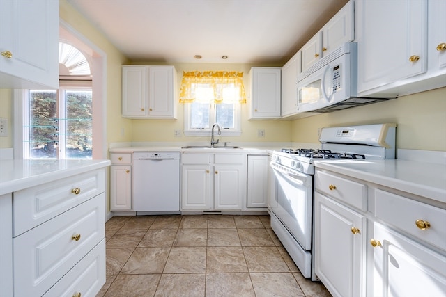 kitchen featuring light countertops, white cabinets, a sink, light tile patterned flooring, and white appliances