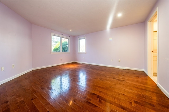 spare room featuring dark wood-style floors and baseboards