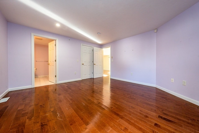 unfurnished room with dark wood-style flooring, visible vents, and baseboards