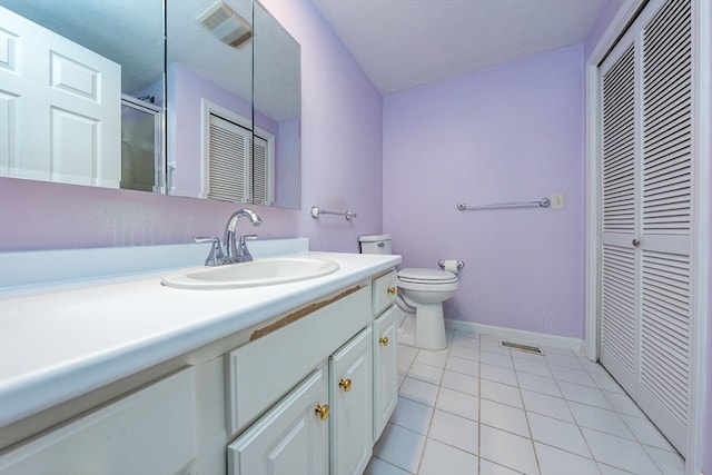 bathroom with a closet, toilet, vanity, baseboards, and tile patterned floors