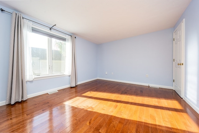 spare room with visible vents, baseboards, and wood finished floors