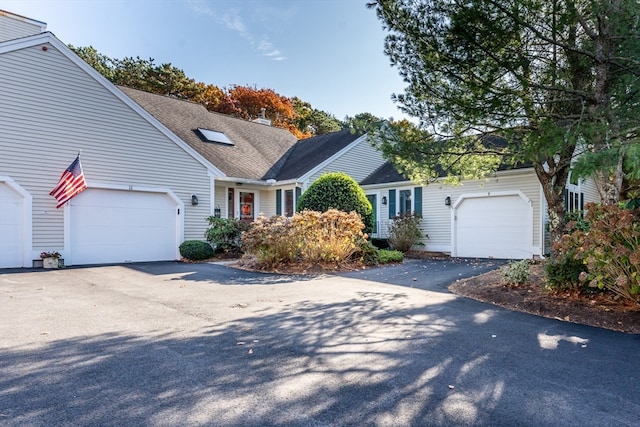 view of front facade with driveway, a chimney, and an attached garage