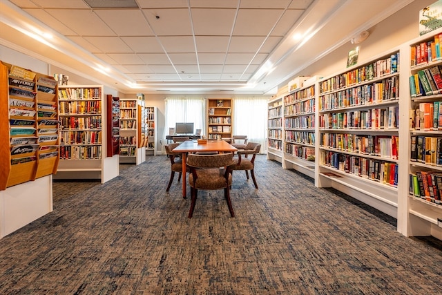 sitting room with bookshelves, dark carpet, and a raised ceiling