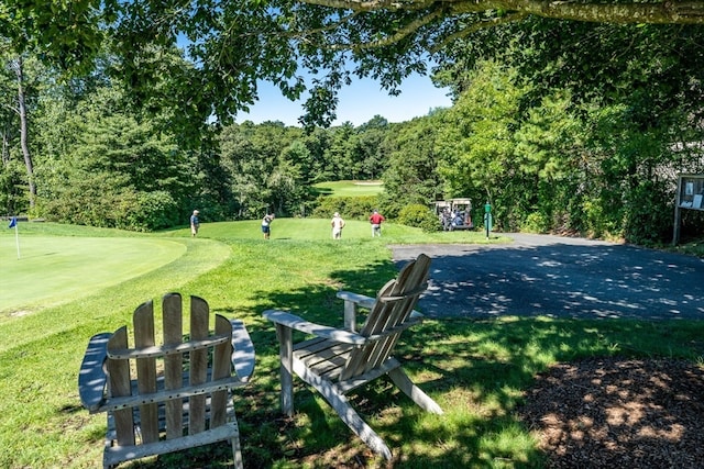 surrounding community with golf course view and a lawn