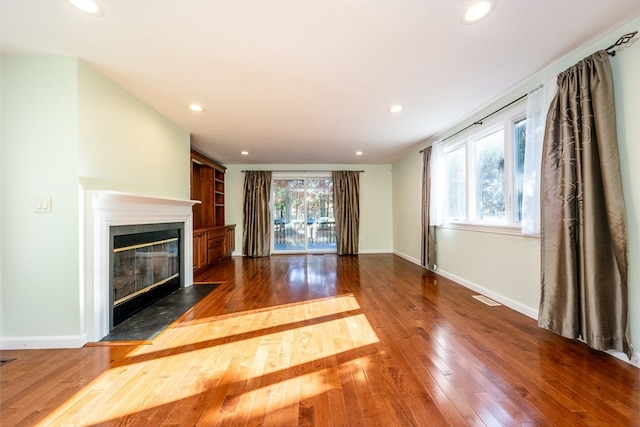 unfurnished living room with a fireplace with flush hearth, recessed lighting, visible vents, and dark wood finished floors