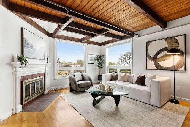 living room featuring wood finished floors, beam ceiling, wood ceiling, baseboards, and a fireplace with flush hearth