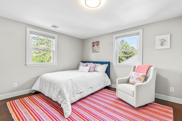 bedroom featuring multiple windows, wood finished floors, and baseboards