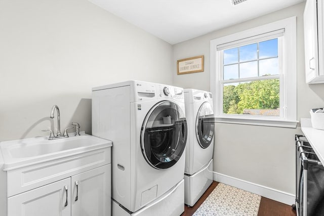washroom featuring cabinet space, independent washer and dryer, dark wood-style flooring, and baseboards