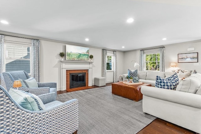 living room featuring wood finished floors, ornamental molding, recessed lighting, and a brick fireplace
