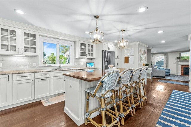 kitchen with stainless steel refrigerator with ice dispenser, a sink, recessed lighting, decorative backsplash, and dark wood-type flooring