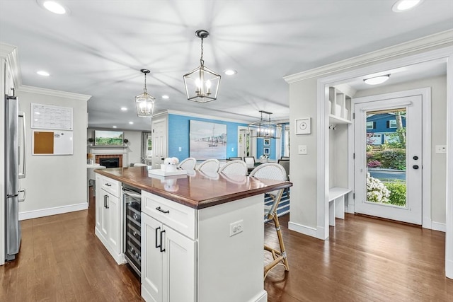 kitchen with freestanding refrigerator, butcher block counters, ornamental molding, wine cooler, and recessed lighting