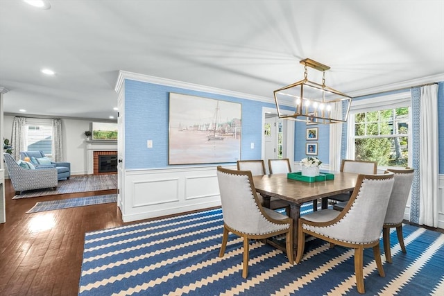 dining room featuring a chandelier, crown molding, hardwood / wood-style floors, plenty of natural light, and wainscoting