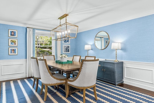 dining space featuring a chandelier, wainscoting, ornamental molding, dark wood finished floors, and a decorative wall