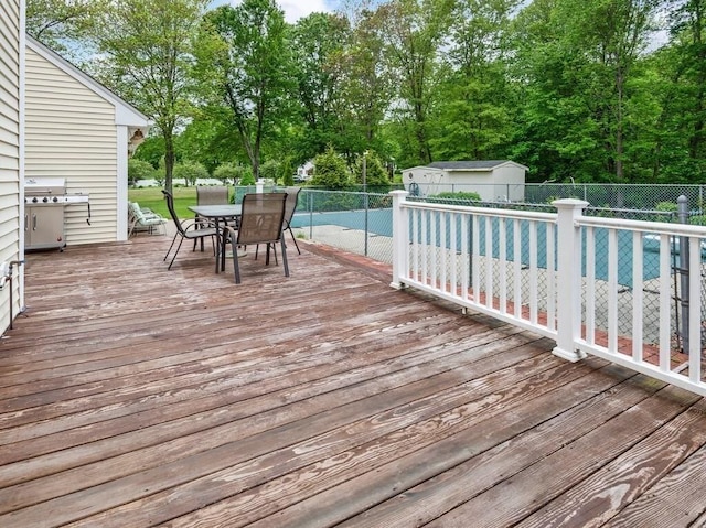 58 Fitzpatrick Rd, Grafton, MA 01519 - wooden deck with outdoor dining space, a fenced backyard, grilling area, an outbuilding, and view of scattered trees