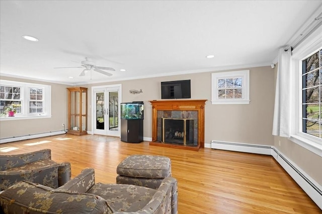 living room with a baseboard heating unit, wood finished floors, a fireplace, and baseboard heating