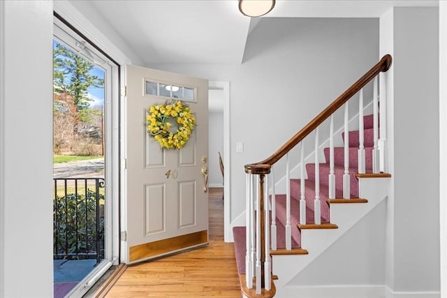 entrance foyer featuring stairway, lofted ceiling, and wood finished floors