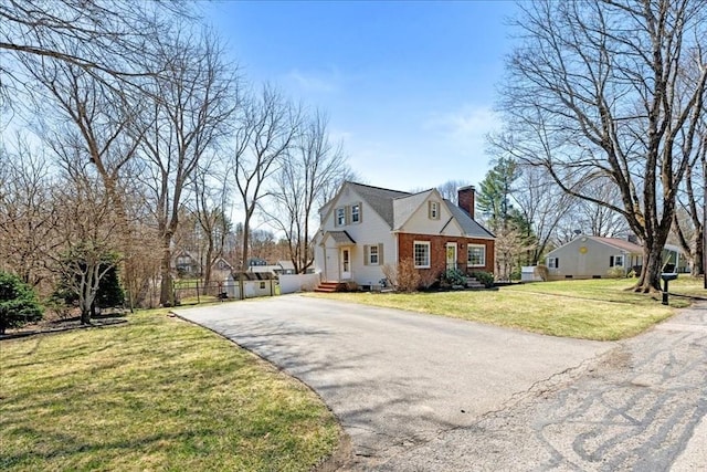 view of front of home featuring a chimney, a front lawn, driveway, and fence