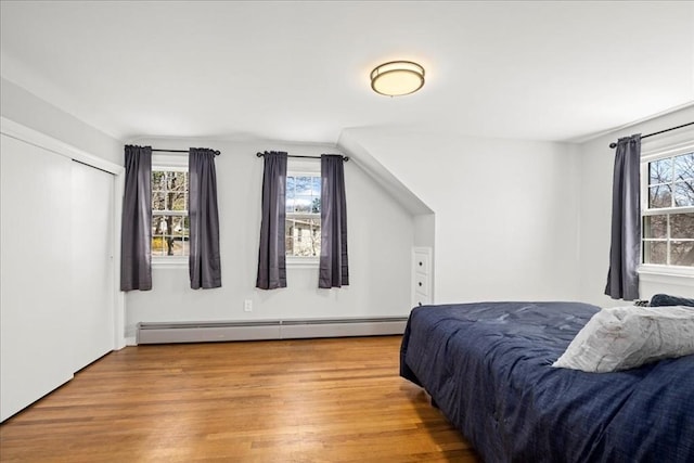 bedroom with a baseboard heating unit and wood finished floors