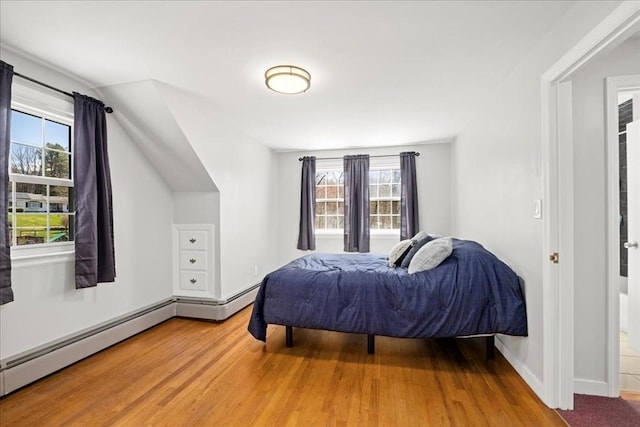 bedroom featuring vaulted ceiling, a baseboard radiator, baseboards, and wood finished floors
