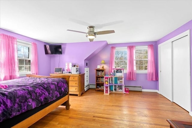 bedroom featuring a baseboard heating unit, light wood-type flooring, a baseboard radiator, and a ceiling fan