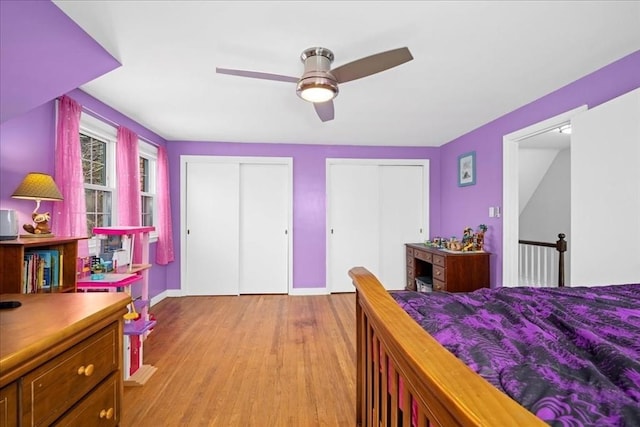 bedroom with light wood-type flooring, multiple closets, baseboards, and ceiling fan
