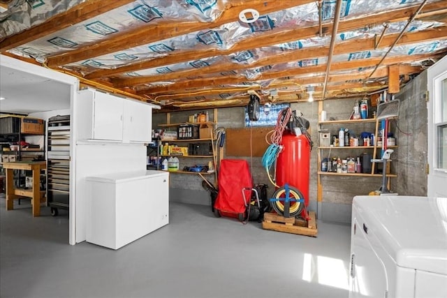 unfinished below grade area featuring refrigerator and washing machine and clothes dryer