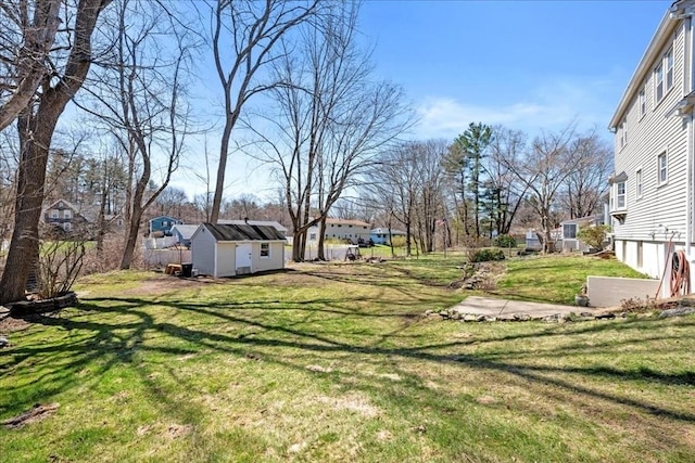 view of yard featuring an outdoor structure, a residential view, and a shed