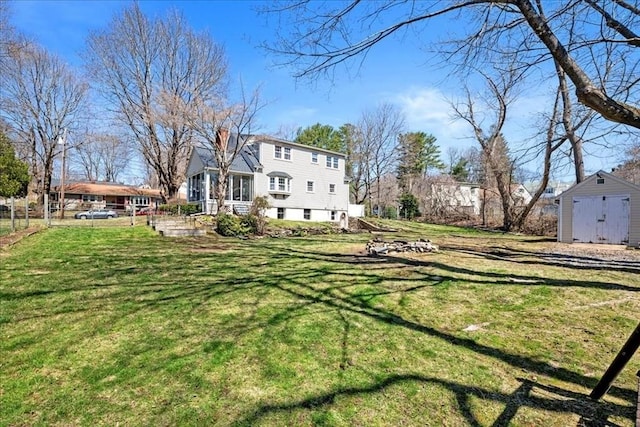 view of yard with an outdoor structure, fence, and a storage shed