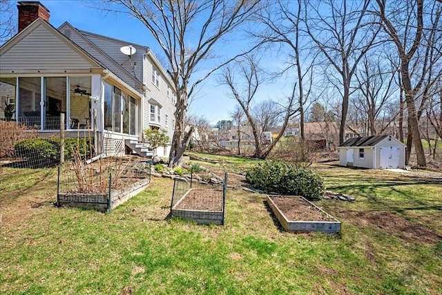 view of yard featuring a shed, a ceiling fan, an outdoor structure, a garden, and a sunroom