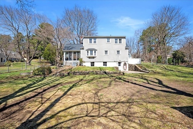 rear view of house with a sunroom and a yard
