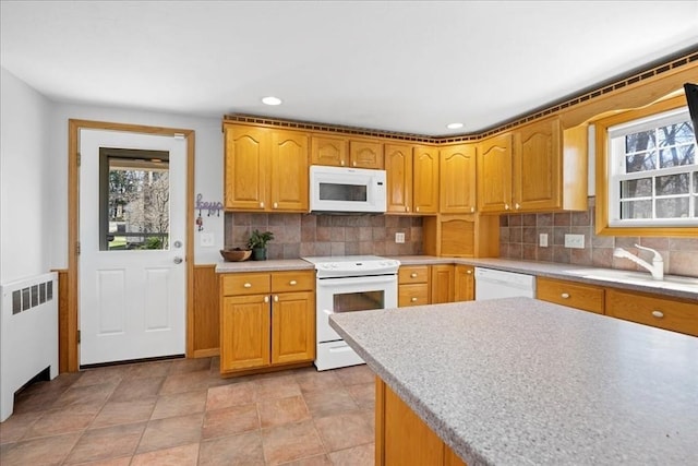 kitchen featuring a sink, radiator heating unit, decorative backsplash, white appliances, and light countertops