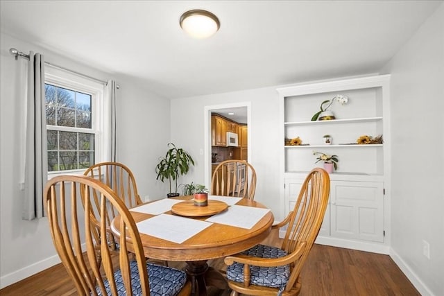 dining space featuring baseboards and dark wood-style flooring