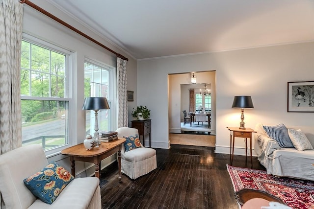 living room with hardwood / wood-style floors, crown molding, baseboards, and a chandelier