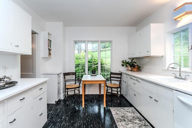 kitchen with a sink, dishwasher, white cabinets, and light countertops