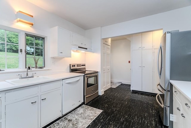 kitchen featuring stainless steel appliances, under cabinet range hood, a sink, light countertops, and white cabinets