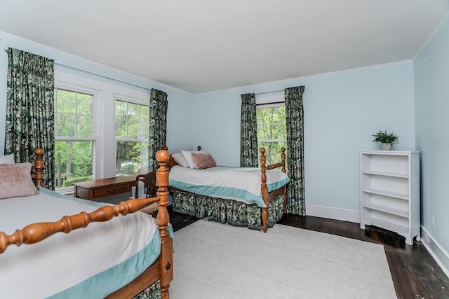 bedroom featuring baseboards, wood finished floors, multiple windows, and ornamental molding