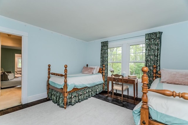 bedroom with wood finished floors, crown molding, and baseboards