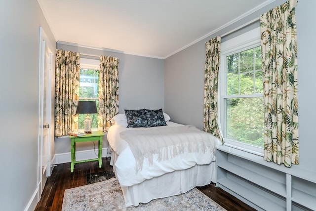 bedroom with wood finished floors, baseboards, crown molding, and multiple windows