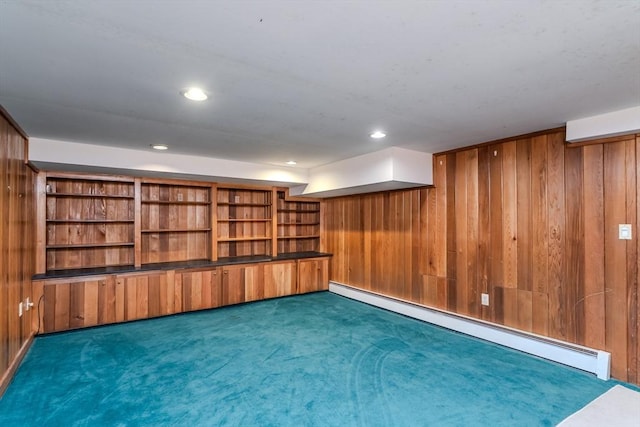 carpeted empty room featuring baseboard heating, wood walls, and recessed lighting