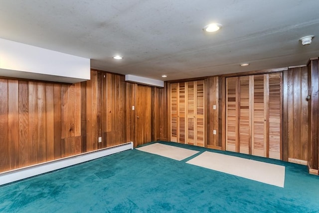 finished basement with a baseboard radiator, wood walls, carpet floors, and recessed lighting