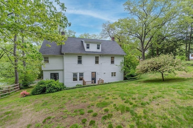 back of property featuring a chimney and roof with shingles